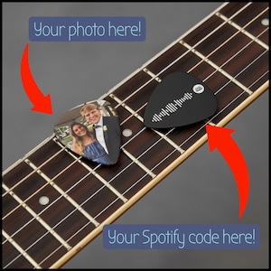 May include: Two guitar picks resting on a guitar fretboard. One pick features a color photograph of a couple, with the text Your photo here! and a red arrow. The other black pick displays a white Spotify code with the text Your Spotify code here!