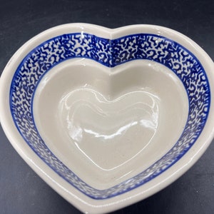May include: A white heart-shaped ceramic bowl with a blue and white patterned design. The bowl is perfect for serving snacks or desserts.