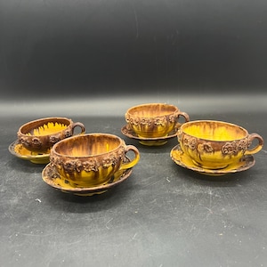 Peut inclure: Ensemble de quatre tasses à thé et soucoupes en céramique brun et jaune avec un motif floral.
