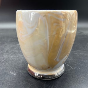 May include: A white and brown ceramic mug with a marbled design. The mug has a silver rim and base.
