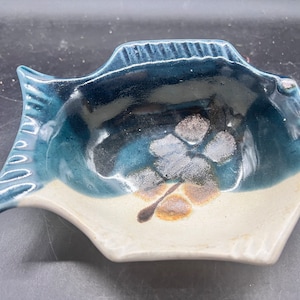 May include: A blue and white ceramic fish-shaped dish with a brown and white floral design.