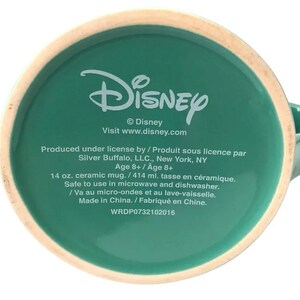 May include: Green ceramic mug with the Disney logo and text that reads "&copy; Disney Visit www.disney.com Produced under license by / Produit sous licence par Silver Buffalo, LLC., New York, NY Age 8+ / Age 8+ 14 oz. ceramic mug. / 414 ml. tasse en c&eacute;ramique. Safe to use in microwave and dishwasher. / Va au micro-ondes et au lave-vaisselle. Made in China. / Fabriqu&eacute; en Chine. WRDP0732102016"