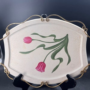 May include: A white oval serving tray with a gold wire handle. The tray has a crackled glaze and a painted design of pink tulips with green leaves.