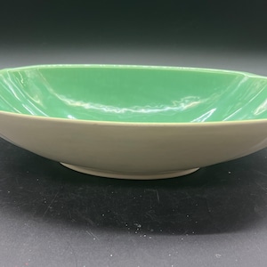 May include: A large, oval-shaped serving bowl with a white base and a light green interior. The bowl has a slightly scalloped rim.