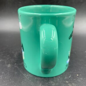 May include: A green ceramic mug with a white handle. The mug has a black and white design on it that says "It's my birthday and I'll cry if I want to".