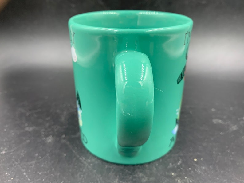 May include: A green ceramic mug with a white handle. The mug has a black and white design on it that says "It's my birthday and I'll cry if I want to".