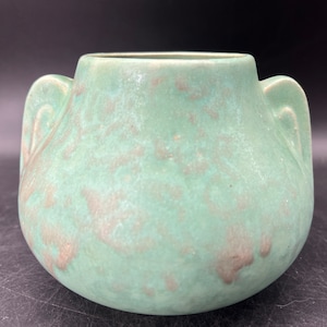 May include: A green ceramic vase with two handles. The vase has a mottled glaze with brown accents.