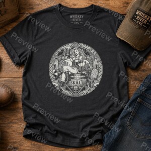 Puede incluir: Una camiseta gris carb&oacute;n de manga corta con un estampado gr&aacute;fico circular blanco. El dise&ntilde;o muestra a una persona sentada sobre un barril sosteniendo una jarra, rodeada de im&aacute;genes vikingas, incluyendo barcos y hachas, con el texto SK&Aring;L abajo.