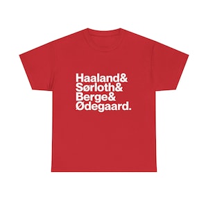 May include: A red short-sleeved t-shirt featuring white text printed on the front. The text lists the names Haaland, Sørloch, Berge, and Ødegaard, each separated by an ampersand symbol, with a period at the end of the final name.