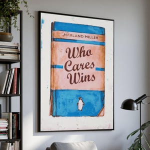 May include: A framed rectangular wall art print featuring a stylized book cover design. The artwork displays the text HARLAND MILLER and Who Cares Wins in dark brown lettering over a peach and blue background with a small penguin illustration.