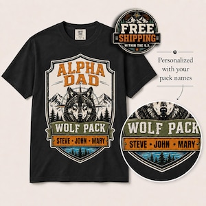 May include: A black short-sleeve t-shirt featuring a graphic print of a wolf head centered within a shield-shaped emblem. The design includes mountains, pine trees, and the text ALPHA DAD WOLF PACK with the names STEVE, JOHN, and MARY below.
