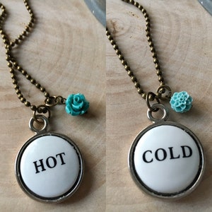 May include: A necklace with a silver pendant that says "HOT" on one side and "COLD" on the other. The pendant is attached to a bronze chain with a turquoise flower charm.