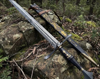 May include: A long, ornate sword with a patterned blade and a black handle, resting on a mossy rock. The sword is accompanied by a black and brown sheath with gold accents. The image is set in a natural, outdoor environment.
