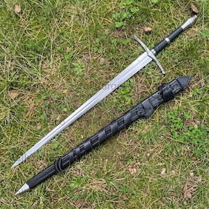 May include: A long steel sword with a double-edged blade, a silver crossguard, and a black grip with a silver pommel. Beside the sword lies a black scabbard featuring a spiral-wrapped design and a leather strap attachment for secure carrying.
