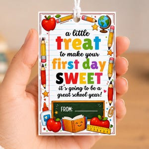 May include: A rectangular white gift tag with a lined paper background featuring colorful school-themed illustrations including apples, pencils, a globe, and a book. The text reads: a little treat to make your first day SWEET it's going to be a great school year! FROM: