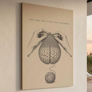 Op de afbeelding: Een rechthoekige wandkunstprint op een beige achtergrond met een zwarte lijntekening van twee handen die een menselijk brein breien met breinaalden. Onder het brein ligt een bol wol met een draad. De tekst luidt: YOU ARE NOT YOUR OLD PATTERNS.