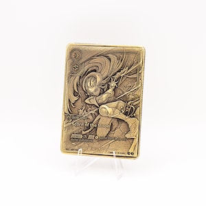 May include: A rectangular gold-toned metal card featuring an embossed illustration of a character with flowing hair. The text reads Legend Diana, Scorn of the Moon, and includes game-related symbols and instructions etched into the metallic surface.