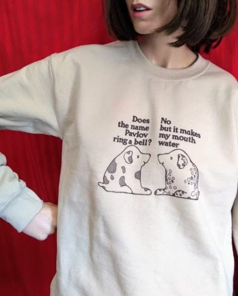 May include: A light beige sweatshirt with a graphic of two dogs and the text "Does the name Pavlov ring a bell? No but it makes my mouth water."