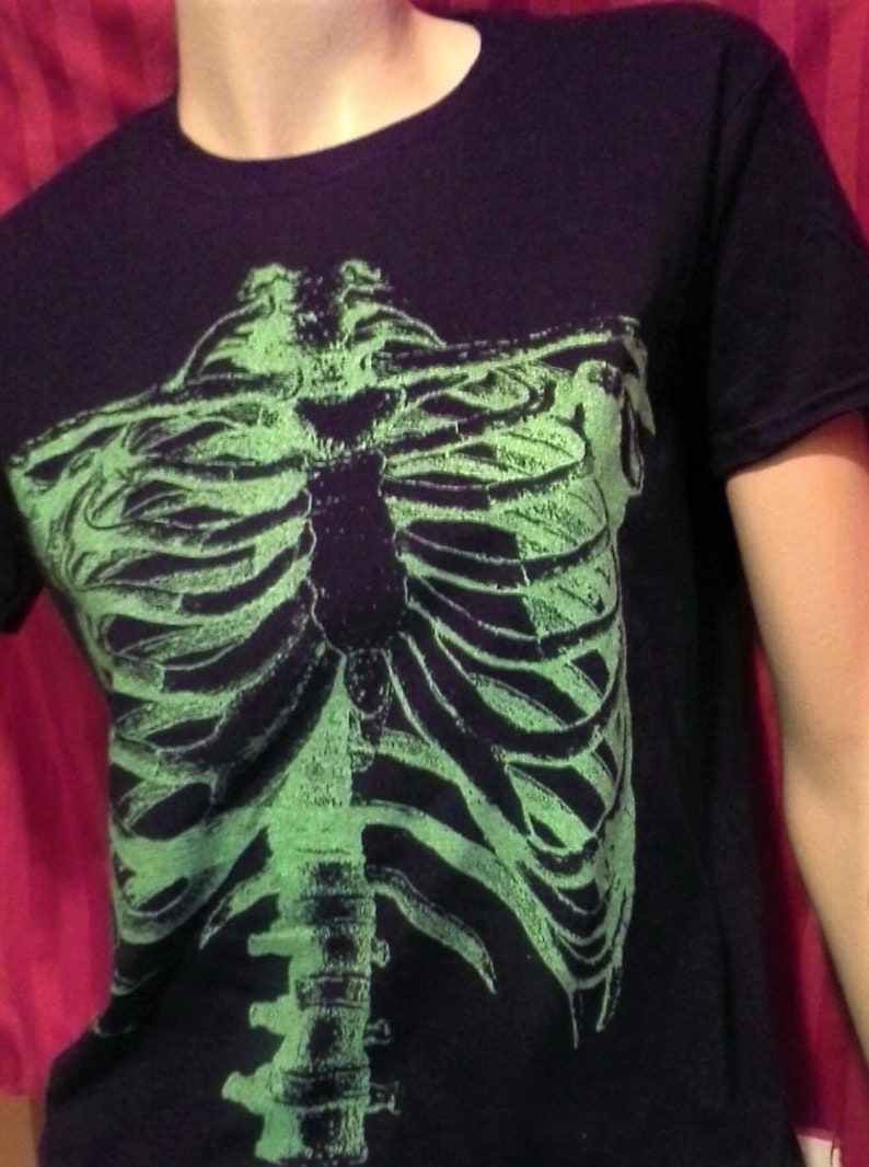 Puede incluir: Camiseta negra con un gr&aacute;fico de esqueleto verde que brilla en la oscuridad en la parte delantera.