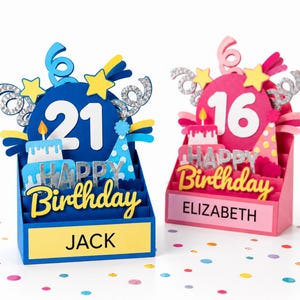 May include: Two 3D pop-up birthday cards. The blue card features the number 21, a cake, a party hat, and the name JACK. The pink card features the number 16, a cake, a party hat, and the name ELIZABETH. Both cards display the text HAPPY BIRTHDAY.