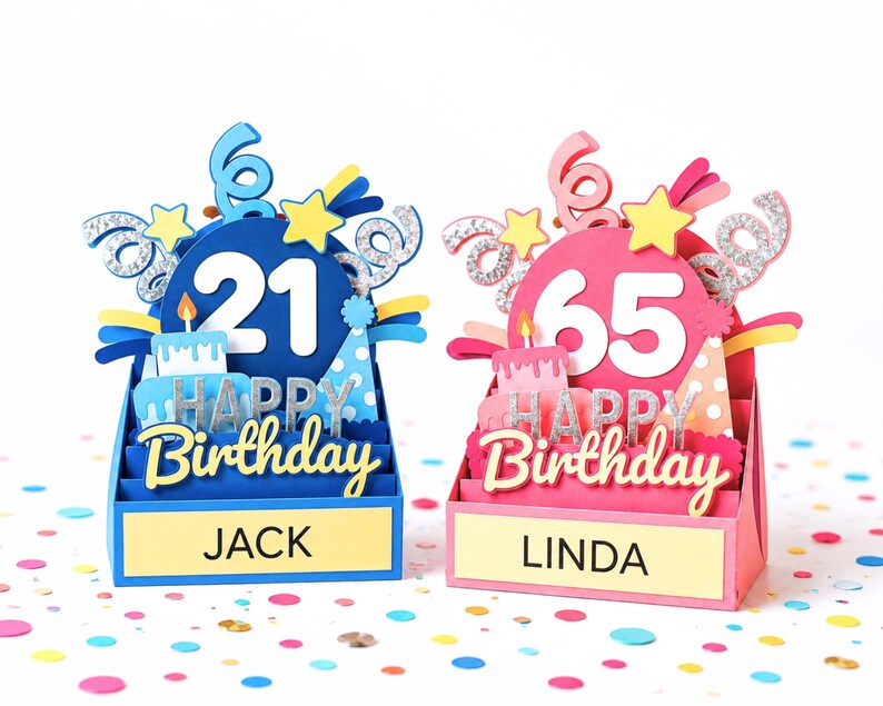 Two 3D customizable paper pop-up birthday cards standing side-by-side on confetti; a blue version for a 21st birthday labeled "Jack" and a pink version for a 65th birthday labeled "Linda," both featuring paper-cut layers of stars, cakes, party hats, and glittery spirals.