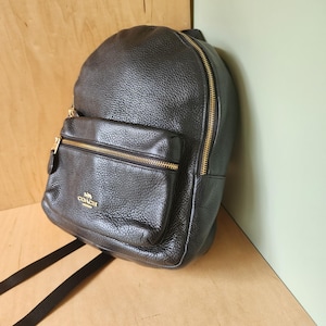 coach flag backpack in pebble leather HENRY Black Signature jacquard refined pebble leather and smooth calf leather Inside zip cell phone and multifunction pockets Inside tech sleeve Drawstring and snap closures fabric lining Top handle with 3 1/4 drop Outside zip and flap pockets Adjustable shoulder straps Luggage sleeve 11 1/4 (L) x 17 3/4 (H) x 6 1/2 (W) Style No. Coach Flag Leather Backpack In