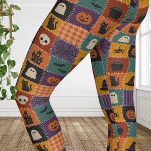 May include: Leggings featuring a patchwork pattern of Halloween-themed squares. The design includes illustrations of orange pumpkins, black cats, white ghosts, skulls, spiders, spiderwebs, bats, cauldrons, witch hats, and haunted houses.