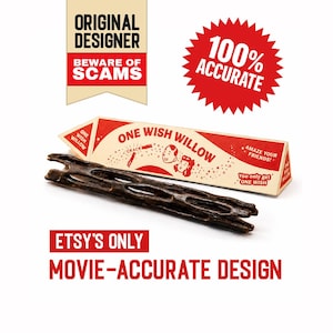 May include: A dark brown, cylindrical, porous wooden stick positioned in front of a triangular cardboard box. The box features red and cream graphics with the text ONE WISH WILLOW, AMAZE YOUR FRIENDS, and You only get ONE WISH, alongside other text.