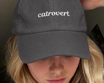 以下が含まれることがあります： フロントパネルに白い筆記体でcatrovertという文字が刺繍されたチャコールグレーの野球帽。この帽子は構造化されたクラウン、カーブしたつば、通気性を高めるために上部パネルに縫い付けられたアイレットを備えています。