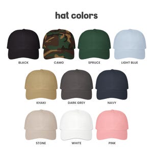 A collection of eleven baseball caps arranged in three rows, labeled with the text 'hat colors'. The caps are available in black, camo, spruce, light blue, khaki, dark grey, navy, stone, white, and pink solid or patterned colors.
