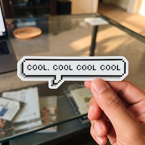 May include: A rectangular white sticker shaped like a speech bubble with a black pixelated border. The text COOL. COOL COOL COOL is printed in the center in a black pixelated font. The sticker features a small downward-pointing tail on the bottom.