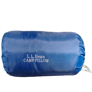 May include: A royal blue rectangular camp pillow with a smooth, slightly reflective finish. The text L.L.Bean CAMP PILLOW is printed in white on the centre of the pillow. A small white drawstring cord is visible on the right side of the item.