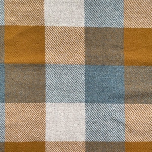 May include: A woven fabric featuring a large-scale plaid pattern in shades of mustard yellow, muted blue, and off-white. The textile displays a distinct diagonal twill weave texture throughout the intersecting colored squares of the checkered design.