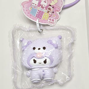 May include: A light purple character figurine wearing a hooded animal costume, encased in clear plastic packaging. The packaging includes a header card featuring cartoon rabbits and the text JICHAOTU and NIENIE, attached to a purple lanyard.