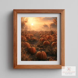 May include: A framed wall art print featuring a pumpkin patch at sunset. The scene displays numerous orange pumpkins resting on dry grass under a golden, hazy sky with trees in the background. The artwork is enclosed in a light brown wooden frame.