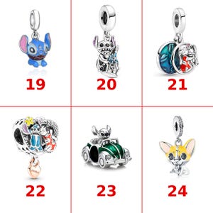 May include: A collection of six silver-toned metal charms labeled 19 through 24. The charms feature various characters and objects, including a blue alien, a castle, a moon, a car, and a yellow dog, with colorful enamel accents and text.