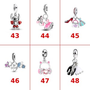 May include: A collection of six silver charms labeled 43 through 48. Charm 43 is a boxing character. 44 features ballet slippers and a dress. 45 shows a shoe, handbag, and dress. 46 has a heart with the word forever. 47 is headphones. 48 shows formal attire.