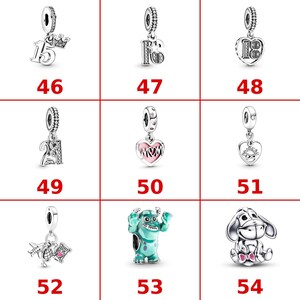 K&ouml;nnte beinhalten: Eine Sammlung von neun silberfarbenen Metallanh&auml;ngern mit verschiedenen Motiven, darunter die Zahlen 15, 16, 18, 21, ein Herz mit dem Wort MOM, ein Herz mit dem Wort FRIENDS, ein Reise-Motiv, ein blaues Monster und ein grauer Esel.