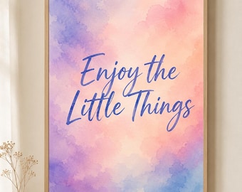 May include: A rectangular wall art print in a light wood frame featuring a watercolor background with blended shades of purple, pink, and orange. The text "Enjoy the Little Things" is printed in a dark blue script font across the center.