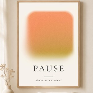 May include: A framed wall art print featuring a soft-focus, gradient square that transitions from orange at the top to a muted yellow-green at the bottom. The text PAUSE is printed in black, followed by a horizontal line and the text there is no rush.