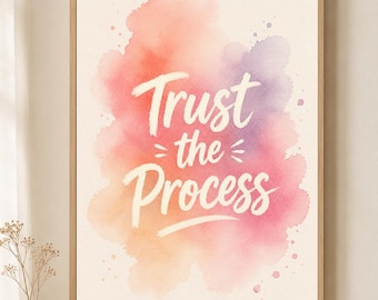 May include: A rectangular framed wall art print featuring the white text Trust the Process centered over a soft watercolor background of blended peach, pink, and purple hues with subtle paint splatters on a light cream-colored paper surface.