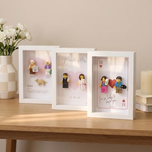 May include: Three white shadow box frames containing custom minifigures. The first frame features two figures and a dog with the text love. The second frame shows a couple with the text Mr & Mrs and 12.20.25. The third frame displays a playing card design with the text I'm so lucky to have you.