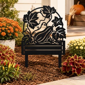 May include: A black metal garden stake featuring a cutout design of a squash or gourd surrounded by large leaves and vines. The silhouette is arched at the top and sits on a rectangular base with two pointed prongs for insertion into the ground.