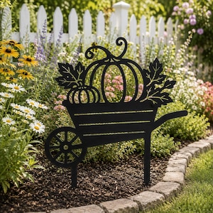 Pode incluir: Um espeto de jardim em metal preto com um design de silhueta de um carrinho de mão cheio de duas abóboras e folhas de outono. A peça decorativa tem uma roda, uma pega e duas pernas pontiagudas para inserir no solo de um canteiro.