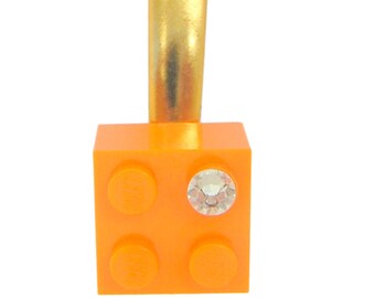 Orange LEGO® brick 2x2 with a ‘Diamond’ color SWAROVSKI® crystal on a Silver/Gold hair clip (one piece)