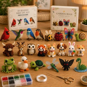 Könnte beinhalten: Eine Sammlung von Tier- und Insektenfiguren aus Perlen, darunter Vögel, eine Biene, ein Marienkäfer, ein Schmetterling, eine Schnecke, ein Bulle, ein Hirsch, eine Eule, ein roter Panda, eine Katze, ein Hund, ein Kaninchen, ein Hamster, ein Frosch, eine Ente, eine Schildkröte, eine Libelle und eine schwarze Motte. Zwei DIY-Kit-Boxen sind sichtbar.