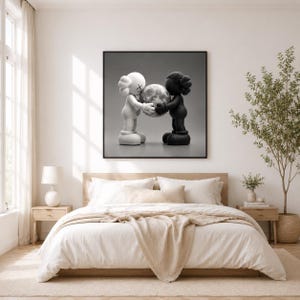 May include: A square framed wall art piece featuring a black and white illustration of two cartoon-style figures, one white and one black, standing face to face and holding a large, textured sphere between them against a plain gray background.