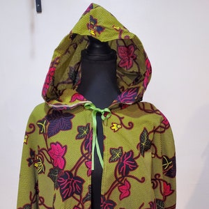 May include: A green hooded jacket with a floral pattern featuring pink, black, and yellow accents. The jacket has a green ribbon tie at the neck.