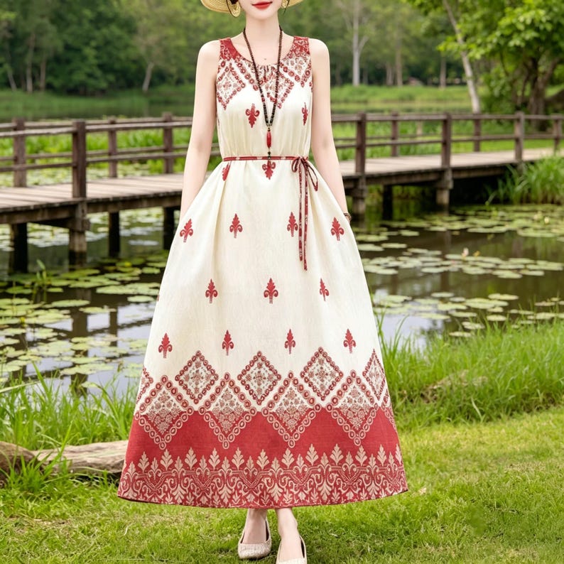 Puede incluir: Vestido sin mangas color crema con estampado floral rojo. El vestido presenta un cuello en V, una cintura anudada y una falda larga y fluida. El dobladillo y el escote est&aacute;n adornados con dise&ntilde;os intrincados. Adecuado para ropa casual.