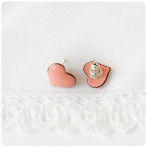 May include: A pair of pink heart-shaped stud earrings with silver posts.